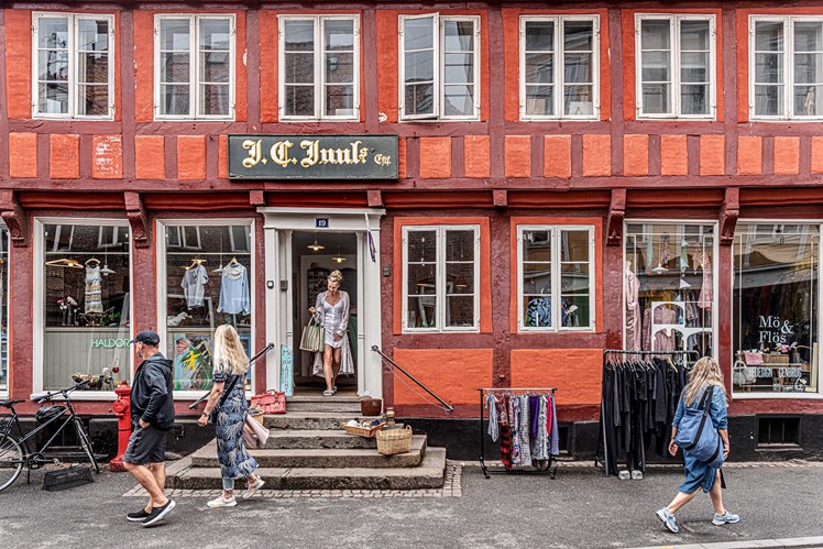 Bag den farverige facade på genbrugsbutikken i Aarhus‘ latinerkvarter gemmer der sig en historie om udsatte og sårbare unge, der får hjælp til at finde balancen i livet. Her får de lov til at prøve deres kreative talenter af – og måske finde ud af, hvad de er gode til, og hvad de brænder for. – Unge i dag føler ofte, at de skal præstere hele tiden. Det skal de ikke hos os. Her skal de først og fremmest være sig selv, siger Mette Prahl.