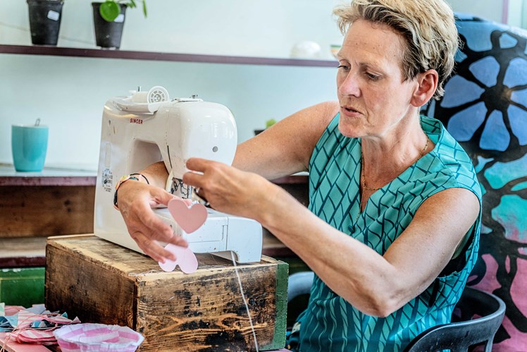Line har handlet her i mange år og er nu også frivillig. Hun passer butikken og redesigner sammen med de unge, der tilknyttes projektet. Hun er uddannet billedkunstner og har undervist i folkeskolen. Dagens projekt for hende er at lave en uro af gamle dækkeservietter af plastic.