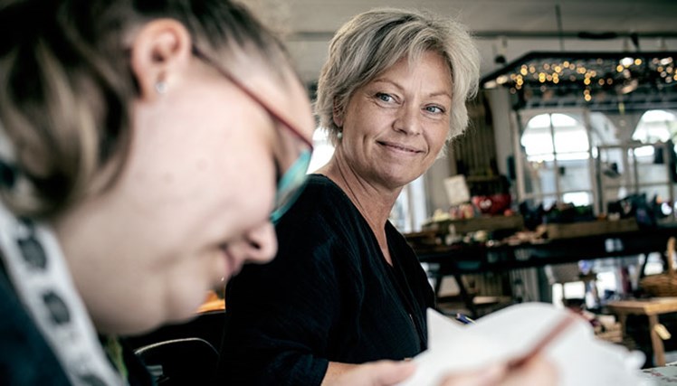 Ejerskab: I Samstyrkens butik på gågaden i Varde laver Sabrina (tv.) trædekorationer til haven. Ifølge pædagog og kunsthåndværker Mette Svane (th.) er det vigtigt, at borgerne kan følge med i, hvordan deres egne kreationer bliver solgt og beundret af kunderne: – Det får dem til at tage ejerskab og mærke, at de bidrager. Så her er der ingen, som føler sig som en omkostning.