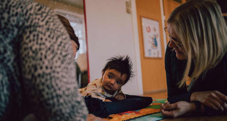 Som familiebehandler kravler socialpædagog Pernille Jensen gerne ned på gulvet for at lave ’ved-siden-af-øvelser’. Som her, hvor hun viser en mor, hvordan man træner barnet i at holde hovedet. 'Det handler om at gøre det, som vi gerne vil have, forældrene skal gøre. På den måde ser og mærker de, hvad det fx betyder, når man har øjenkontakt med barnet', siger hun.