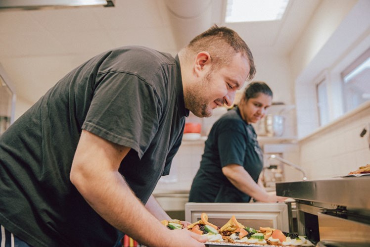Gastronomisk medbestemmelse: Hver dag klokken 12.00 samles medarbejdere og personale fra Højagergaards ni værksteder i kantinen. I dag står menuen bl.a. på smørrebrød, som er Ameds specialitet. Skulle han blive i tvivl om komponenterne til æggemadden, slår han op i en gennemsigtig plasticlamineret bog, der lag for lag illustrerer ingredienserne.