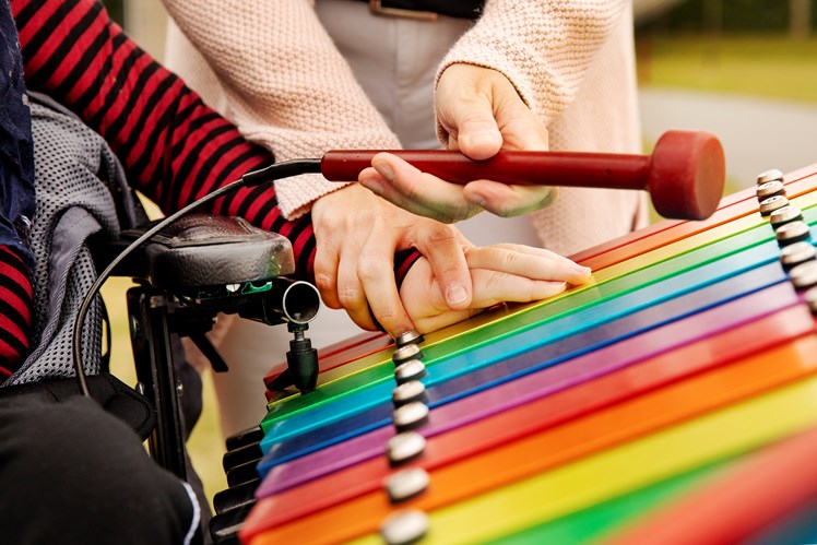 Selv børn med spasticitet kan med den rette støtte gribe fat i de lette plastikkøller og ramme en af de farverige taster på den store xylofon – og så er der skabt musik. Idéen med de såkaldte Percussion Play-udendørsinstrumenter er netop, at de er lettilgængelige, og at alle kan spille med – også selvom man ikke har de store fysiske kræfter.