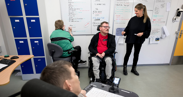 Før var det personalet, der redigerede Lejbjerg Nyt, men den opgave har en af borgerne, Elisabeth, nu overtaget. På dagens redaktionsmøde skriver hun på tavlen, hvor meget plads de forskellige artikler må fylde i det næste nummer. Socialpædagog Kamilla Pretzmann (th.) sikrer sig, at alle i redaktionsgruppen kommer til orde, mens de gennemgår og kommenterer artiklerne. Henrik er chefredaktør. Sammen med Mette (forrest) har han skrevet en artikel om, da de var til chilismagning i det grå værksted.